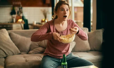 Chica delante de la TV sorprendida con popcorns