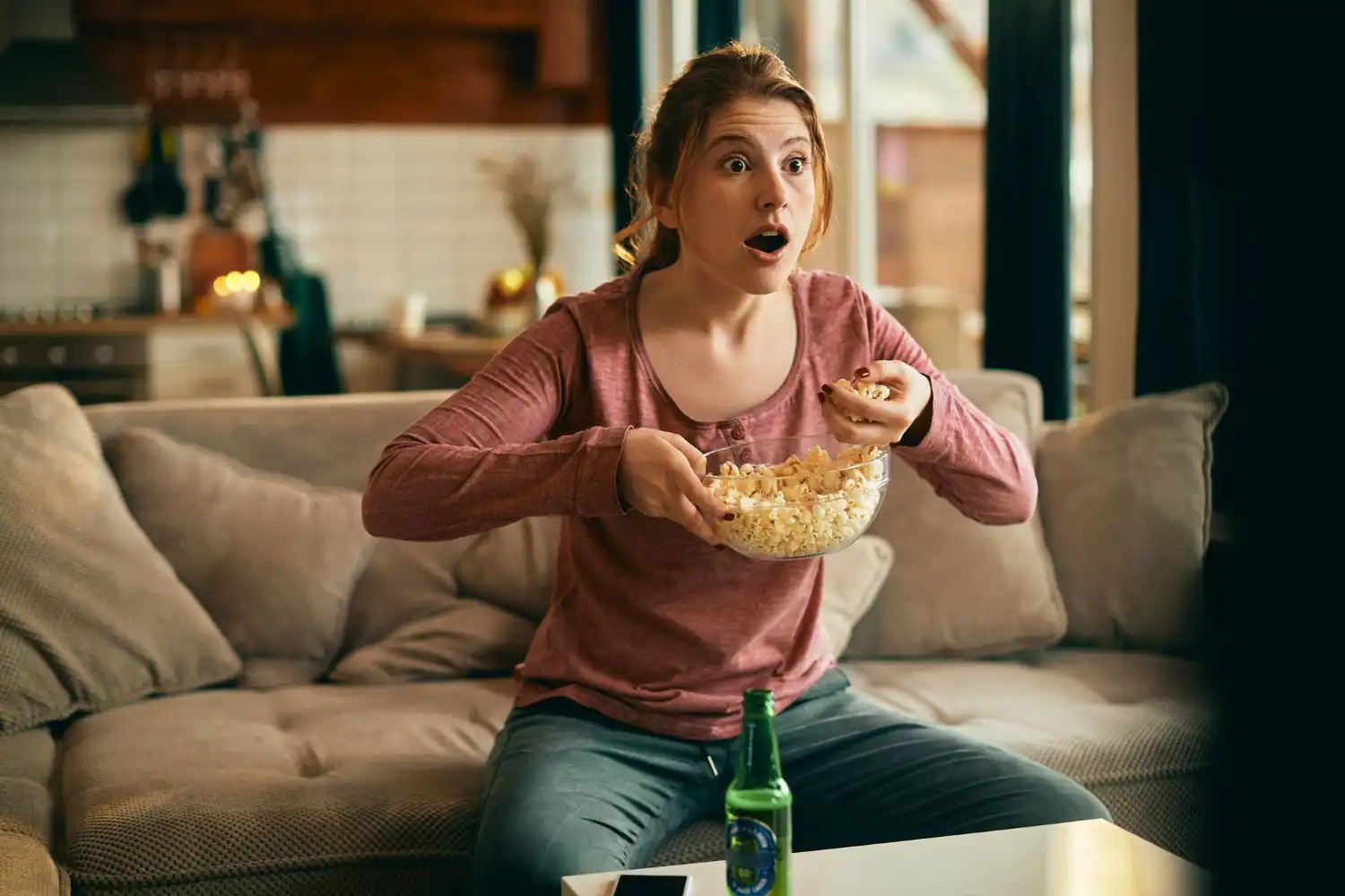 Chica delante de la TV sorprendida con popcorns
