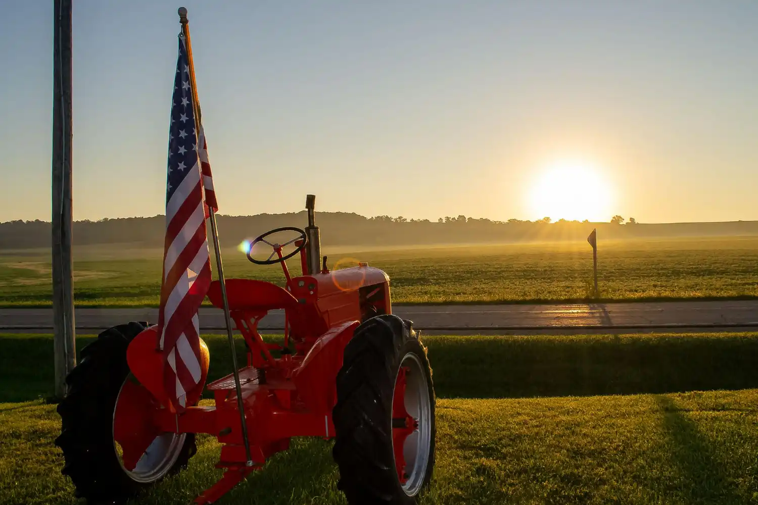Tractor con bandera de EEUU delante de un campo
