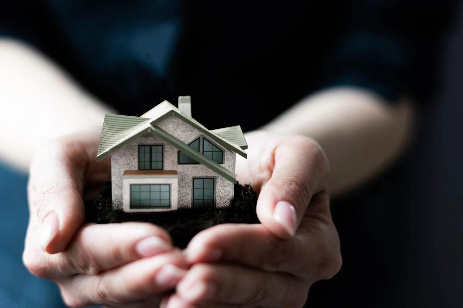 manos que sujetan casa en miniatura